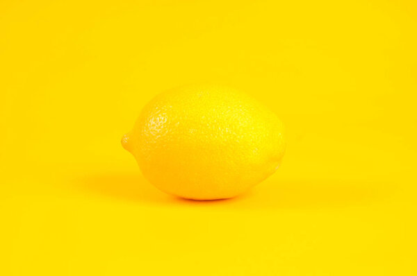 Single lemon isolated on yellow background