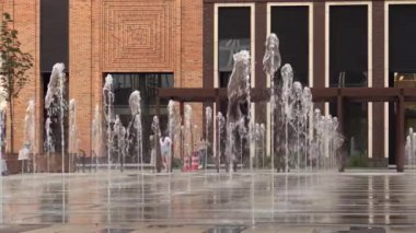 Bir yaz akşamı bahçelerinde fıskiyelerin yanında oynayan çocuklar.