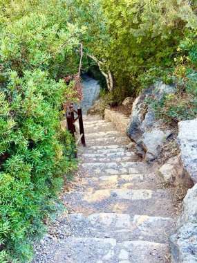 Aşağı inen merdivenler taştan yapılmış. Dışarıdaki yemyeşil çimenlikte beton yol.