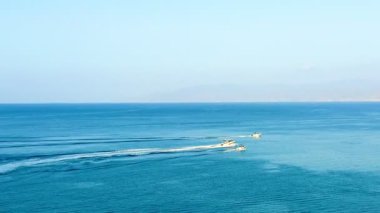 Halk plajı, yaz mevsimi, güzel güneşli hava. Resimli plaj, kumlu kıyıya vuran dalgalar. Deniz dalgaları kayalara çarpıyor. Kıbrıs adası, şemsiyeler, turist botları, Akdeniz.