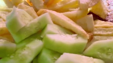 Prepared food: fried potatoes, sliced fresh cucumber, pork burger patty. Close-up of the prepared portion on a white plate.