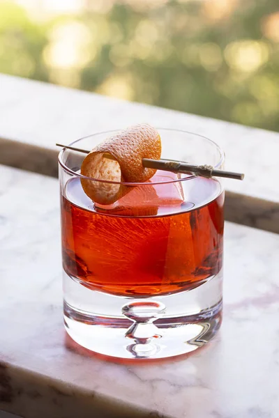 两个红色的内格罗尼鸡尾酒饮料在冰与橙色扭曲大理石窗台 — 图库照片