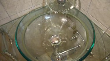 Cam lavabo düşüyor ve bir drenaj gidiş bir musluk gelen su