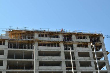 Bina mavi gökyüzü karşı işçilerin siluetleri ile yapım aşamasında