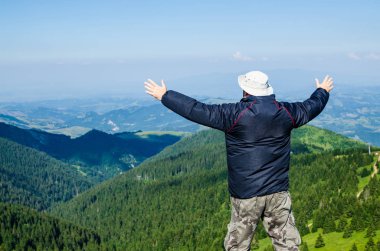 Neşeli poz, bir dağ manzarası kollarında yayılmış olan adam
