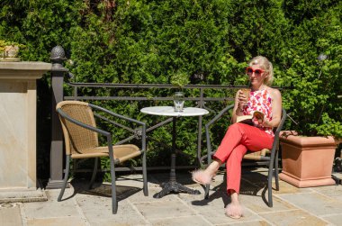 Bir kadın kahve içiyor ve okuyor.