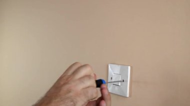 Bir tornavidayla ışık düğmesini duvardan ayırmak