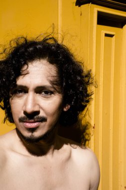 Sakal ve kıvırcık siyah saçlı latin adam portresi. Çıplak gövde