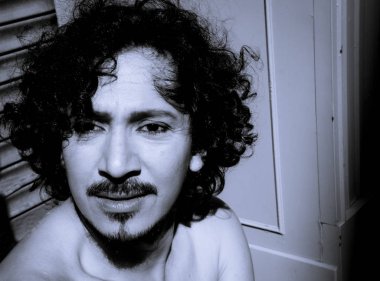 Sakal ve kıvırcık siyah saçlı latin adam portresi. Çıplak gövde
