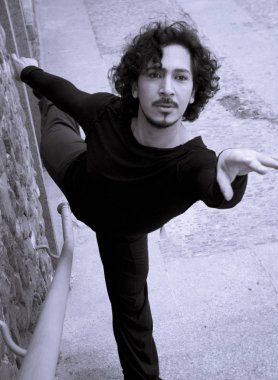 Erkek dansçı bir klasik bale tek ayak üzerinde dönüş yapıyor. Kentsel arka plan