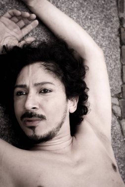 Sakal ve kıvırcık siyah saçlı latin adam portresi. Çıplak gövde