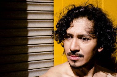 Sakal ve kıvırcık siyah saçlı latin adam portresi. Çıplak gövde