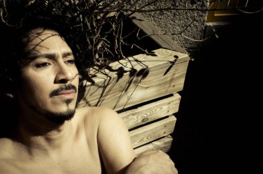 Sakal ve kıvırcık siyah saçlı latin adam portresi. Çıplak gövde