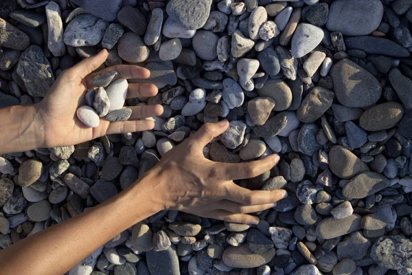 女性の手はビーチで石に触れる 灰色の石 — ストック写真
