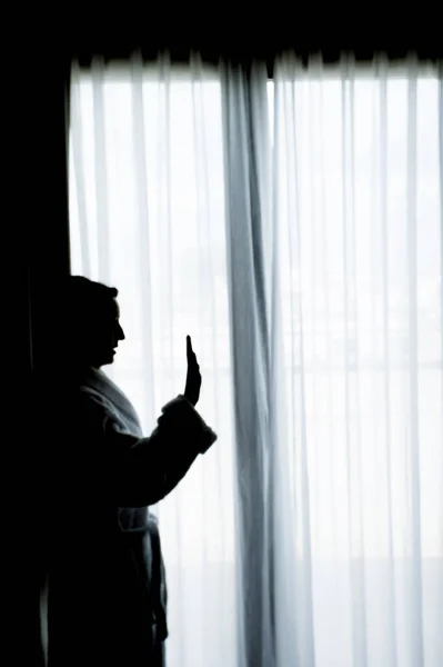 Silhouette of woman with bathrobe in front of a window. Sad atmosphere