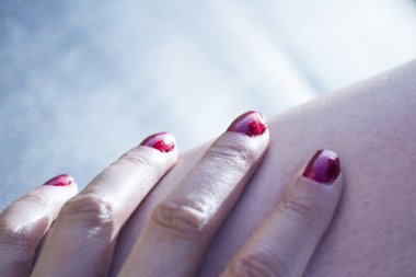 Tırnakları kırmızıya boyanmış kadınlar el ele tutuşur.