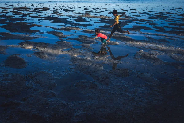 Denawan Island, Sabah Malezya: 29 Nisan 2016 - iki kadeh bir plajda çalışan çocuklar. Bu eylem çekim dahil bir kişi atlama ve diğer düşme.
