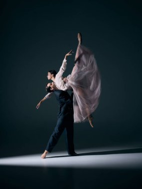 Sahne ışıkları altında duygusal pozlar veren bale partnerleri. Çağdaş sahne sanatı, anlamlı hareket, romantizm ve kültürel kimlik kavramı.