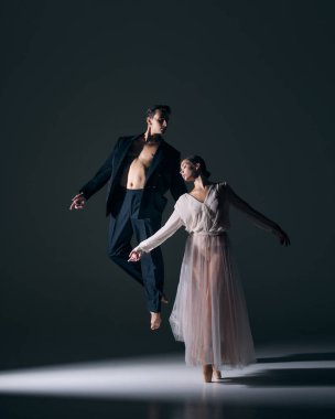 Bale partnerleri dramatik spot ışıkları altında dengeli yükselişte. İfade sanatının konsepti, sahne performansı, düet ahengi, insan bağlantısı, teatral hikaye anlatımı ve tutku.