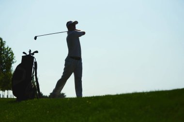 Golfçü golf çantasıyla açık hava sahasında salıncak siluetini bitiriyor. Aktif yaşam tarzı, spor disiplini, sağlık, rekabet ve açık hava eğlencesi kavramı.
