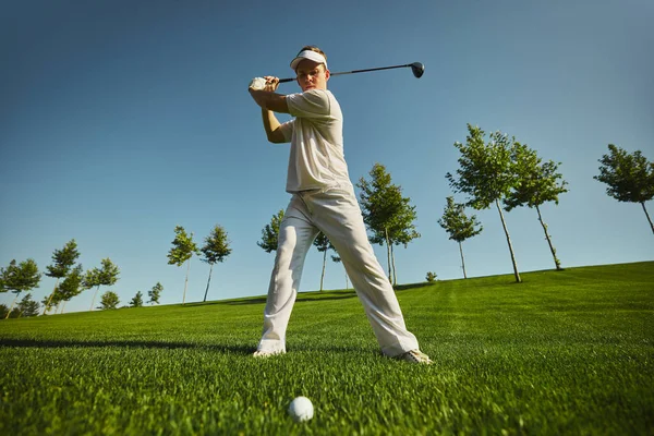 Golfçü geriye doğru pozisyonunu alarak golf topuna vurmaya hazır. Odaklanma, uygulama, açık hava aktivitesi, güç, hassasiyet ve spor mücadelesi kavramı.