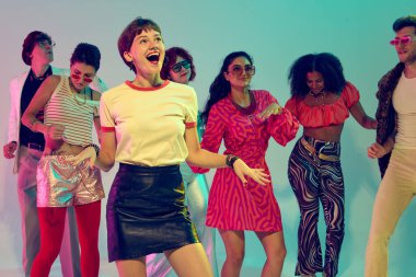 Etrafı renkli arkadaşlarla çevrili dans eden gülümseyen bir kadın. Mutluluk kavramı, yaşam tarzı kutlaması, yaratıcı ifade ve müzik kültürü.