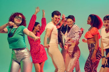 Farklı arkadaş grupları neon ışıkların altında neşeyle dans ediyor. Parti kültürü, kutlama, gençlik yaşam tarzı, müzik ifadesi ve kolektif mutluluk kavramı.