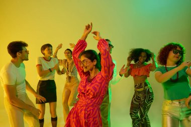 Pembe elbiseli kadın neonlu retro grubuyla el kaldırıyor. Eğlence kavramı, gece hayatı kutlaması, kültürel moda, retro performans ve mutlu topluluk enerjisi..