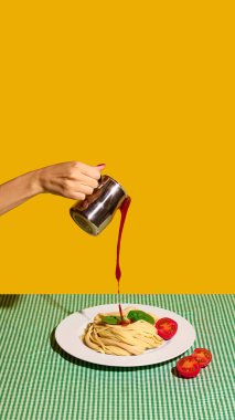 Metal bardaktan domates sosunu fesleğenli ve dilimlenmiş domatesli makarnaya döküyorum. İtalyan mutfak reklamları, yemek kitabı tasarımı, yemek afişleri, yemek tarifi eğitimi ve restoran markası kavramı.