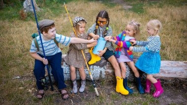 Bir grup kauçuk botlu çocuk dışarıda oynarken su bidonlarını paylaşıyorlar. Takım çalışması, eğitim, çevre dostu çocukluk, aile hayatı ve çocuklara açık hava modası tanıtımı kavramı.