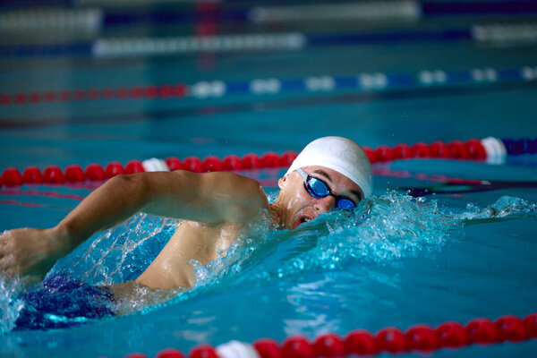 Сосредоточенный пловец занимается фристайлом в бассейне. Концепция спортивной журналистики, плавательной рекламы, фитнес-образа жизни и прогресса медицинской реабилитации с определенными эмоциями.