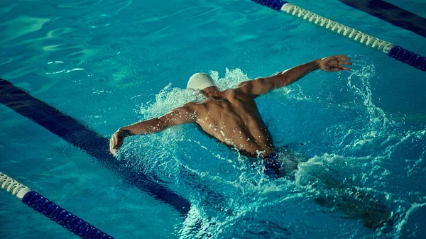 Rekabetçi yüzücü kelebek vuruşunu güçlü bir şekilde yapıyor. Seçkin spor eğitimi, yüzme eğitimi, sağlık, fitness, motivasyon ve güçlü duygularla kararlılık kavramı.