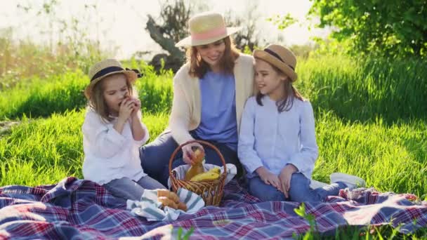 Mamma med döttrar på picknick på gräsmattan och äta frukt — Stockvideo