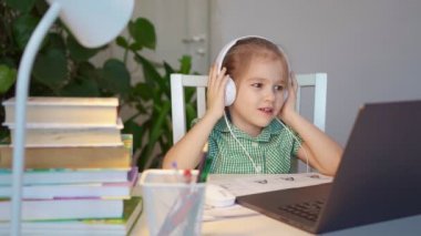 Kulaklıklı çocuk ders dinliyor, uzaktan internet üzerinden ev öğreniyor.