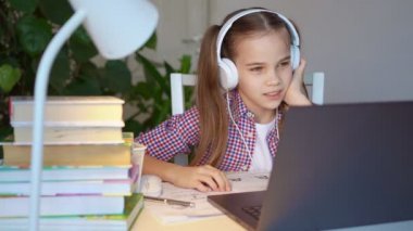 Kulaklıklı genç kız ders dinliyor, uzaktan internet üzerinden ev öğreniyor.