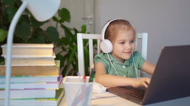 Niña en los auriculares escucha la lección, la distancia en línea de aprendizaje en casa — Vídeo de stock