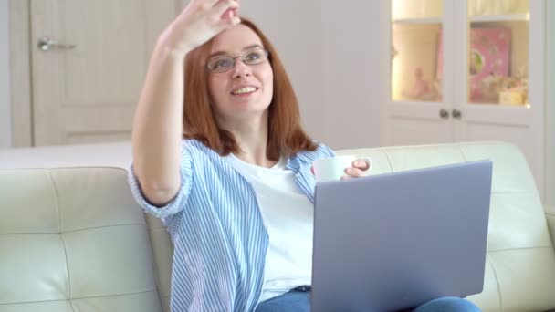 Kobieta robi selfie siedzi na kanapie i weryfikuje sieci społecznościowe na laptopie. — Wideo stockowe