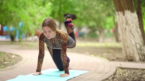 Női sportoló részt vesz fitness a parkban, csinál láb liftek szőnyegen. — Stock videók