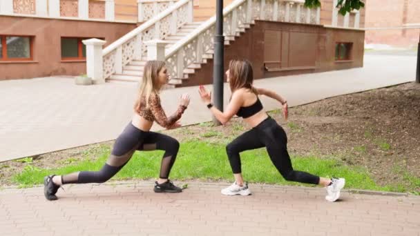 Filles athlètes en vêtements de sport, faire des fentes, étirement dans le parc . — Video