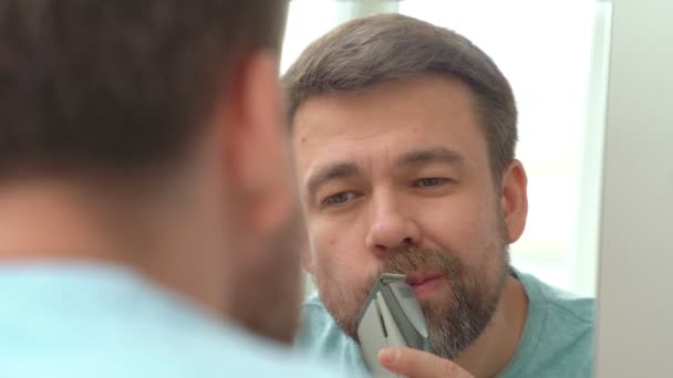 Hombre hace el corte de la barba y el bigote con una navaja de afeitar en casa . — Vídeos de Stock