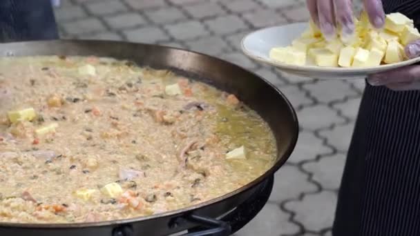 Lägga till smör i risotto med skaldjur kokta på utomhus i pan. gatumat. — Stockvideo