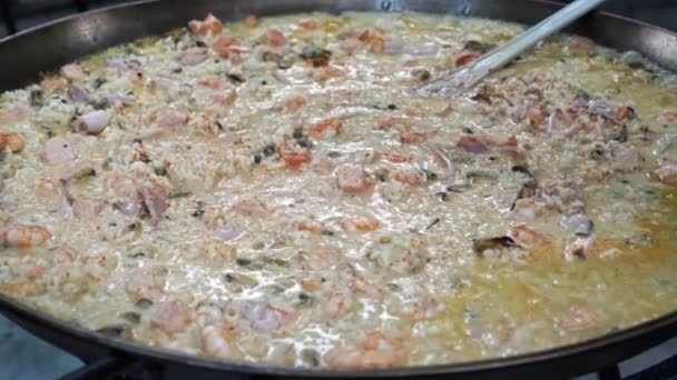 Tillsätt grovt salt i risotto med skaldjur tillagade på utomhus i pan. gatumat. — Stockvideo