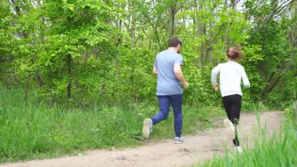 Vista posteriore. gestisce papa 'con un bambino. sentiero in boschetto o luogo per lo sport . — Video Stock