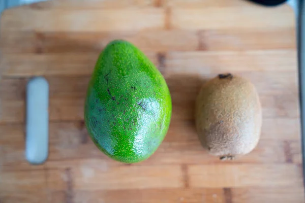 Large green avocados and kiwi fruit on wooden Board cooking healthy diet. — Stock Photo, Image