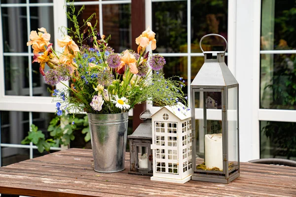 Stůl v zahradě venkovského domu. svícny a kytice květin. — Stock fotografie