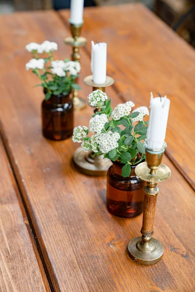 Dekor jídelní stůl, svíčky a malé bílé květy. — Stock fotografie