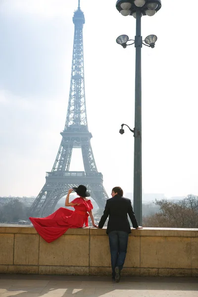 Hombre y mujer vestidos de rojo y sombrero en la Torre Eiffel de París. símbolo de Francia . — Foto de Stock