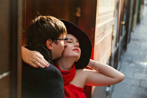 빨간 모자를 쓴 남자와 여자가 좁은 유럽 거리를 껴안고 있습니다. 로맨틱 함. — 스톡 사진