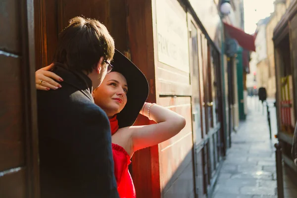 Man and woman in red and hat hugging on narrow European streets. romantic. — Stock Photo, Image