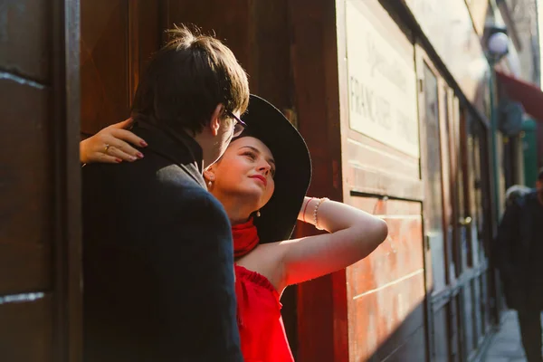 빨간 모자를 쓴 남자와 여자가 좁은 유럽 거리를 껴안고 있습니다. 로맨틱 함. — 스톡 사진